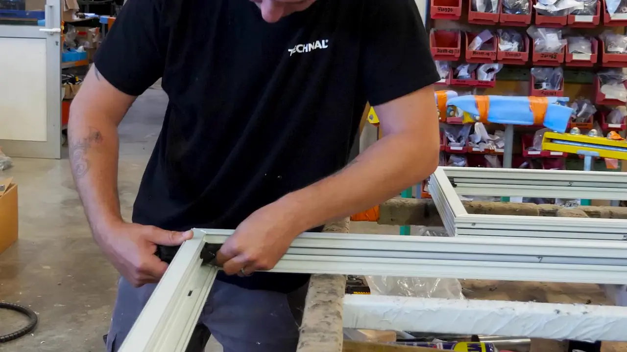 Un menuisier assemble l’angle d’un cadre de fenêtre blanc