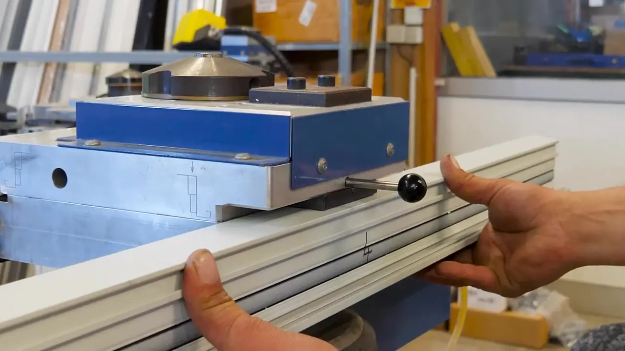 Un profilé glissé dans une presse d’atelier bleue, tenu à deux mains