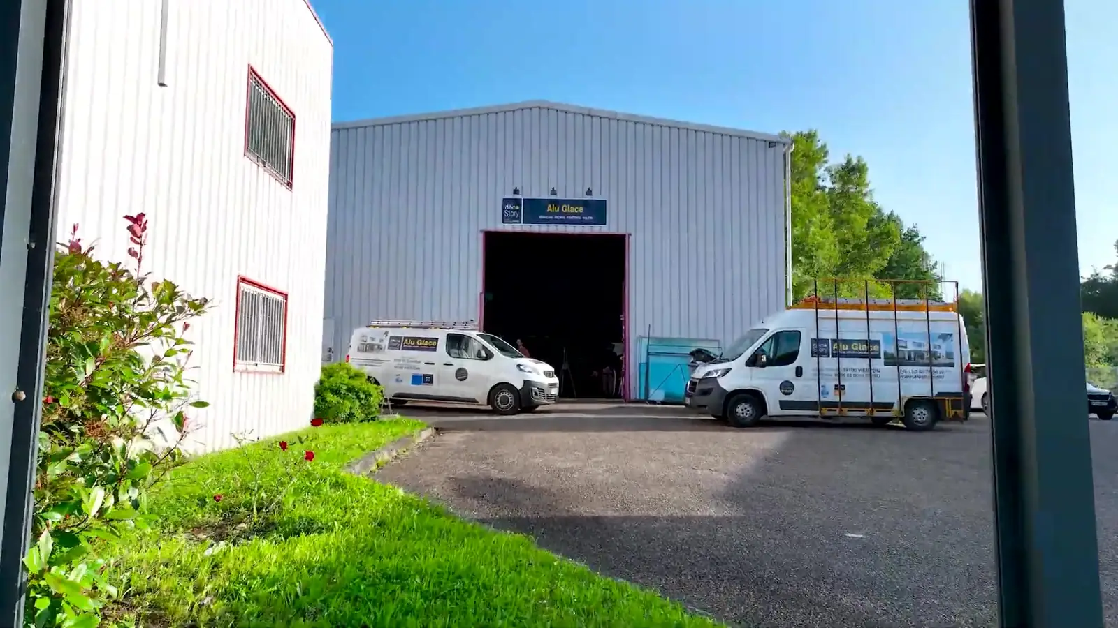 Bâtiment de l’atelier Alu Glace à Vierzon, grande porte ouverte, deux camionnettes blanches