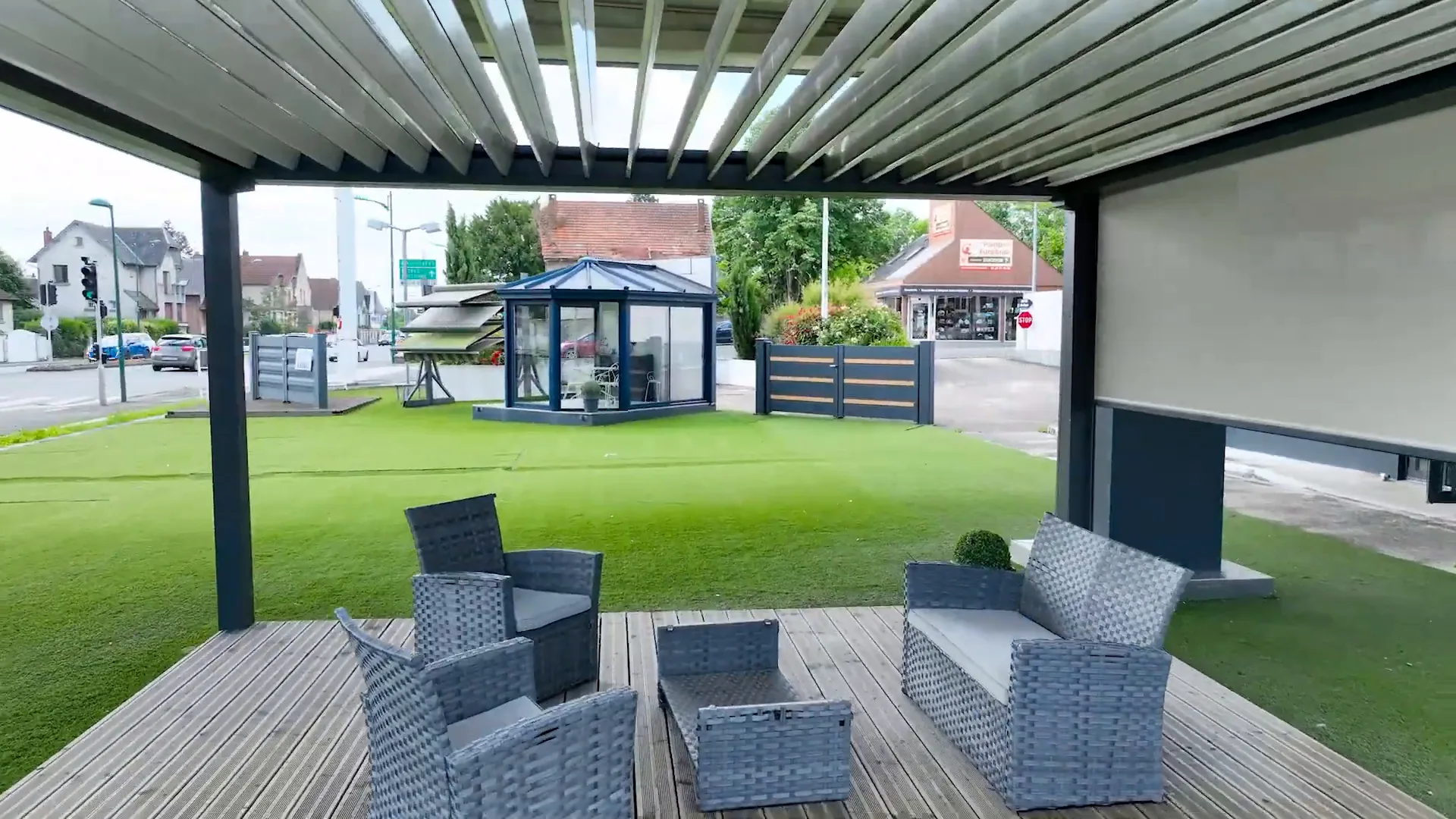 Salon de jardin sous une pergola à lames orientables ouvertes, store vertical sur le côté