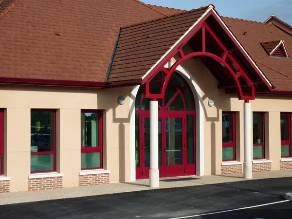 Entrée à double porte rouge sous un fronton cintré, fenêtres rouges assorties
