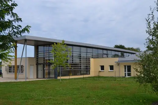 Bâtiment à grande façade vitrée sur deux niveaux sous un auvent sur poteaux