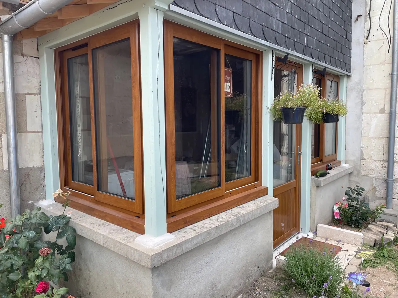 Fenêtres d’angle et porte ton bois posées sur un soubassement en pierre