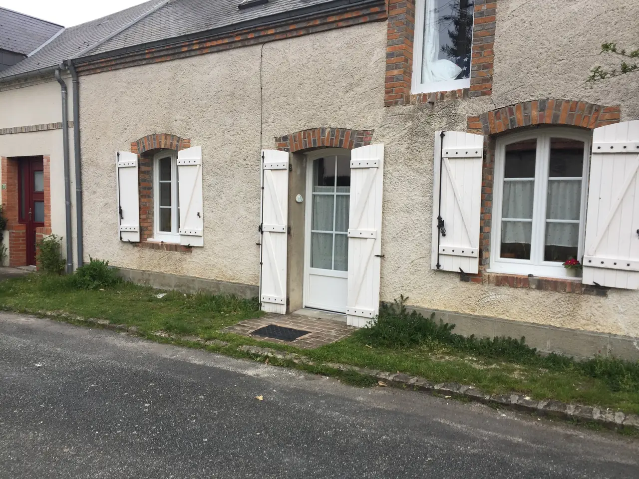 Façade de maison de village aux fenêtres, porte et volets battants blancs