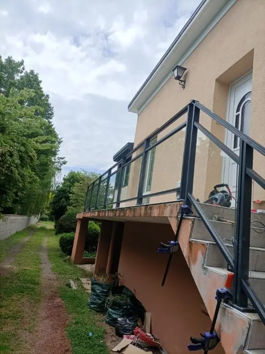 Garde-corps gris anthracite à remplissage transparent en cours de pose sur une terrasse surélevée