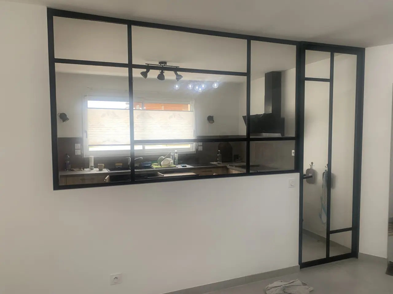 Verrière d’intérieur noire et porte vitrée devant une cuisine