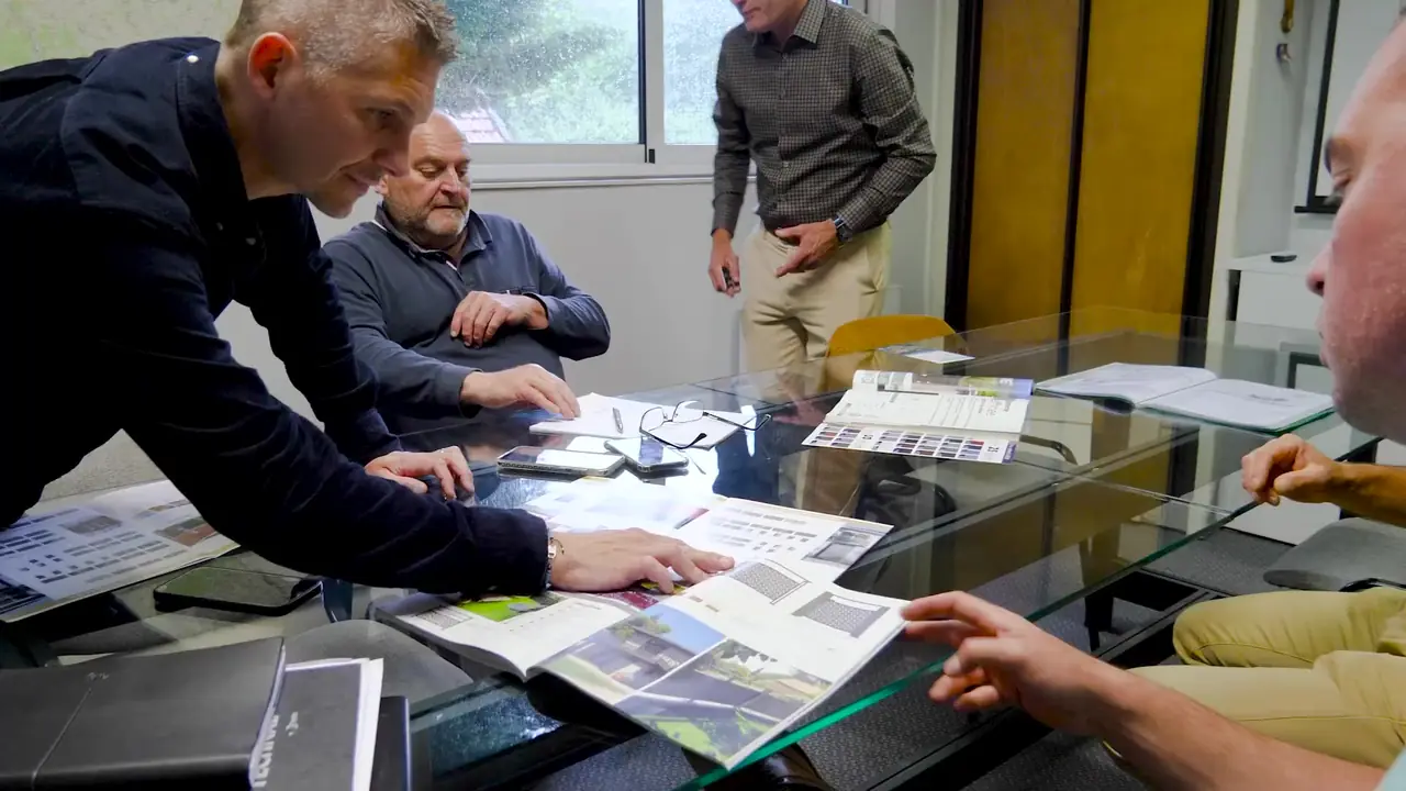 Quatre personnes autour d’une table en verre couverte de catalogues
