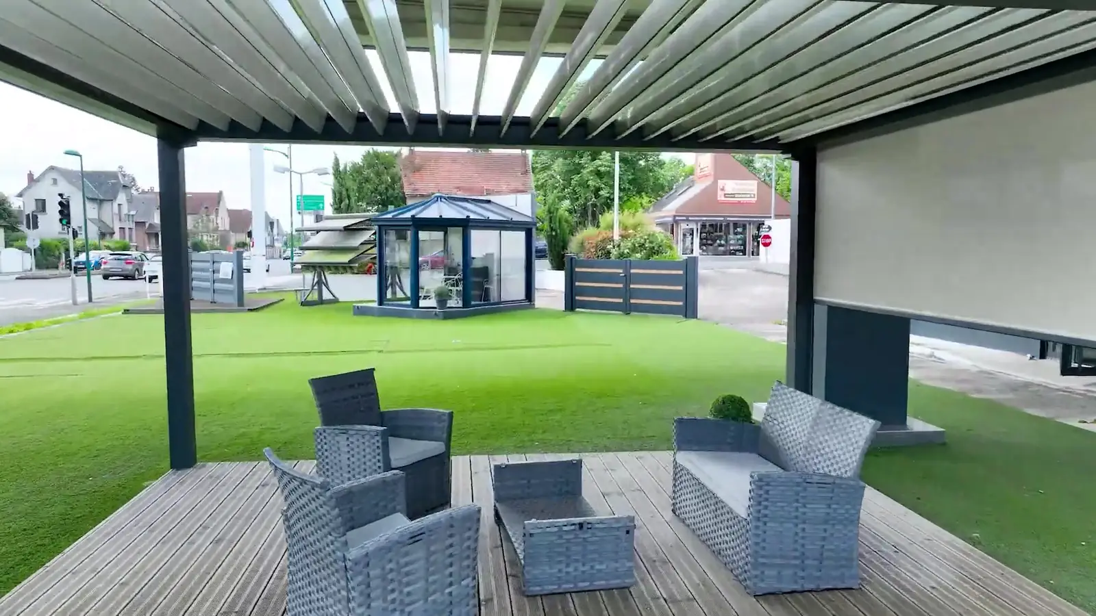 Salon de jardin sous une pergola à lames orientables ouvertes, store vertical sur le côté