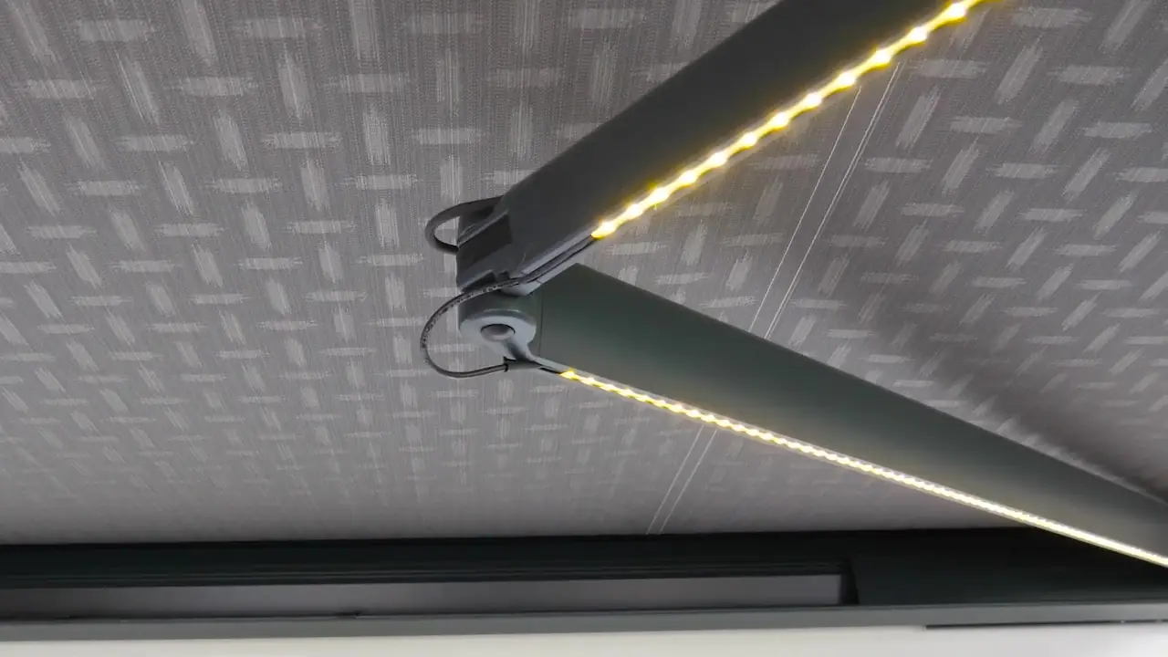 Bras de store banne équipé d’un éclairage LED, sous une toile grise à motifs