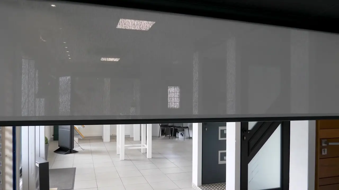 Toile screen grise à demi déroulée dans un local d’exposition